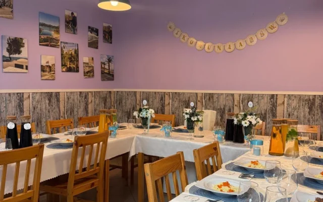 Sala pizzerii Tabia z fioletowymi ścianami: stoły nakryte na przyjęcie komunijne, nad nimi girlanda „Komunia Św.”