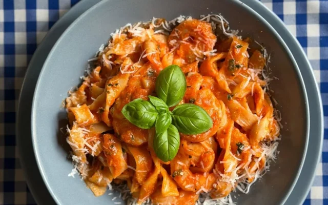 Tagliatelle w sosie pomidorowym z krewetkami, parmezanem i listkami bazylii w szarej misce